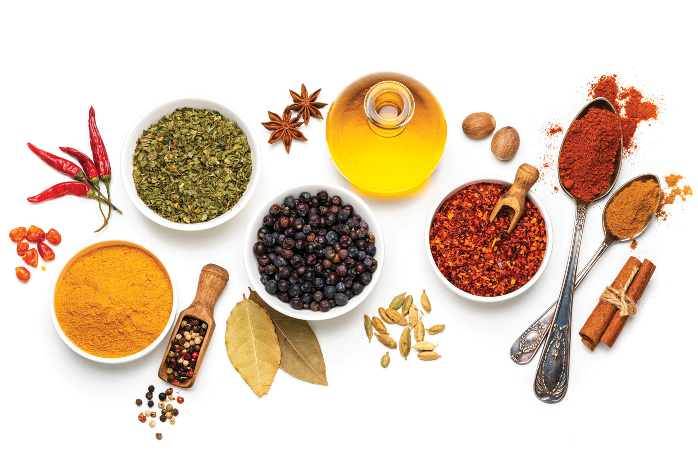 overhead view of several bowls and spoons with multicolored spices